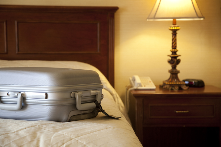 walizka leżąca na łóżku hotelowym
